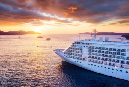 Passenger ship sailing into horizon in the sunset 